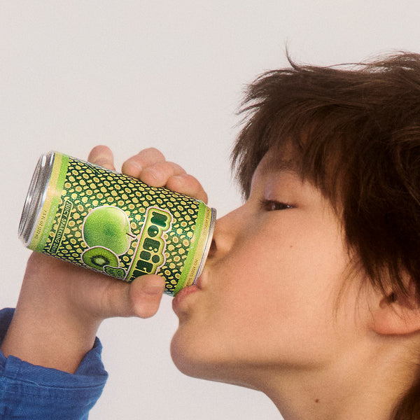Person drinking from green Qoo beverage can with honeycomb pattern design